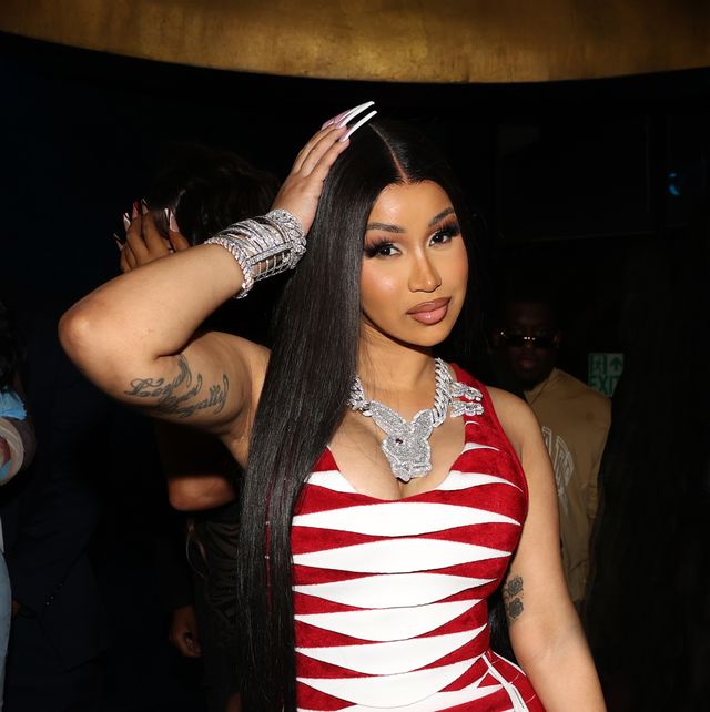 cardi b with thigh length straight black hair a red and white dress and heavy diamond jewellery