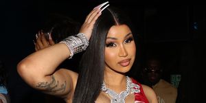 cardi b with thigh length straight black hair a red and white dress and heavy diamond jewellery