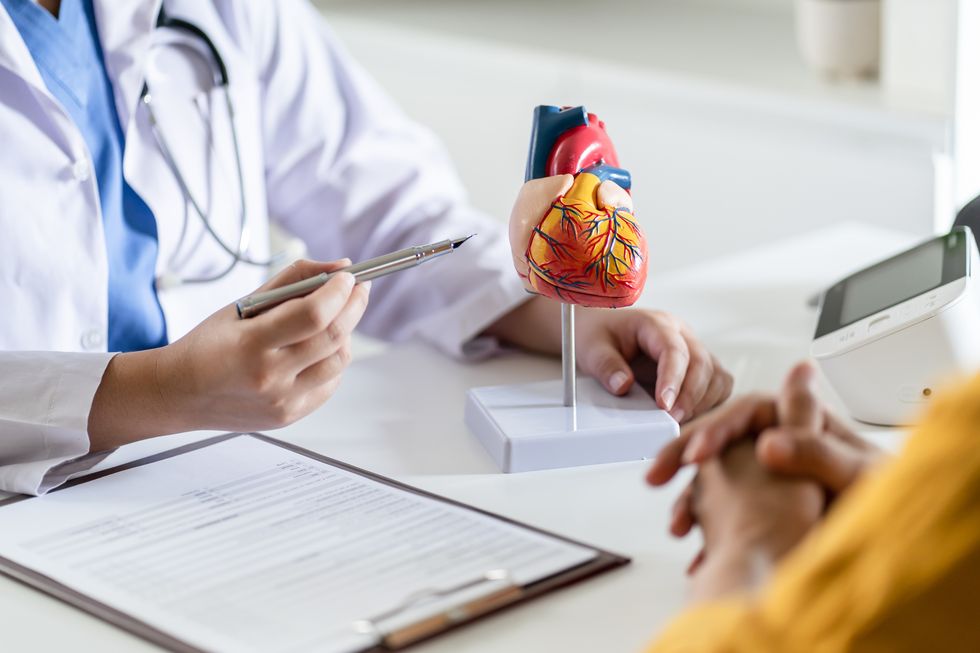 cardiology consultation treatment of heart disease doctor cardiologist while consultation showing anatomical model of human heart with aged patient talking about heart diseases