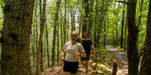 pavlina and john running Rosa on a trail in jacobsburg park 2023
