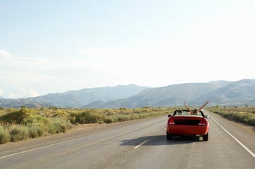 carefree couple driving convertible on desert road