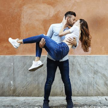 carefree couple in love kissing in front of a wall outdoors