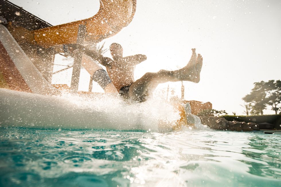carefree man having fun while sliding into the swimming pool