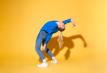 a woman does a backbend against a yellow wall