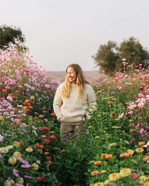 woman farmer stands in a field of wild flowers