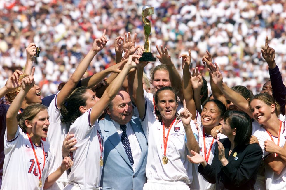 Carla Overbeck (C) holds up the World Cup trophy a
