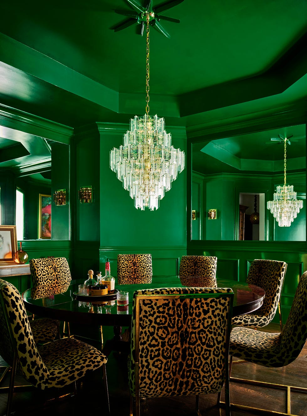 a green dining room with a round table, surrounded by chairs in an animal print fabric