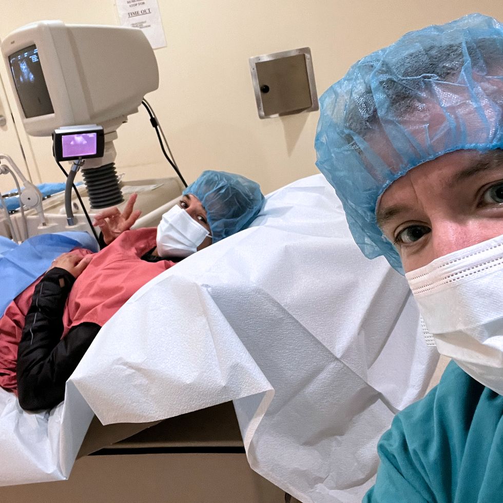 a man in surgical scrubs looking at a baby