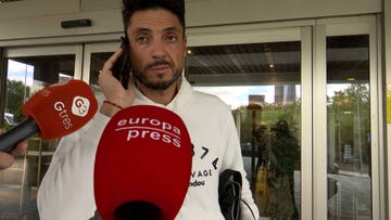 person on a phone call with reporters nearby