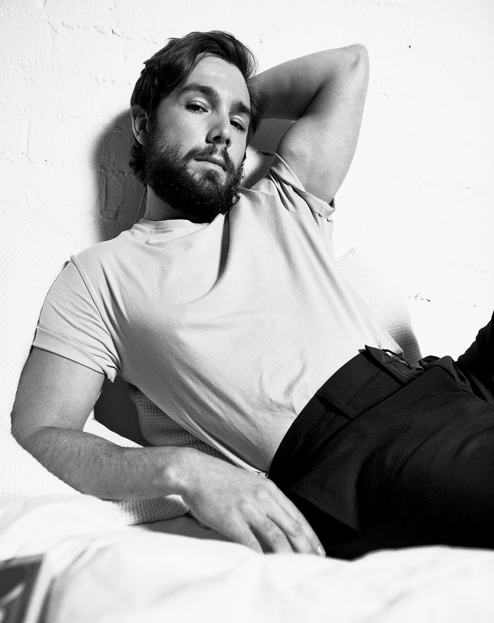 el actor carlos cuevas en camiseta tumbado en la cama en una sesión de fotos para la revista esquire
