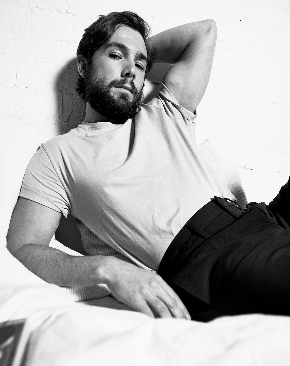 el actor carlos cuevas en camiseta tumbado en la cama en una sesión de fotos para la revista esquire