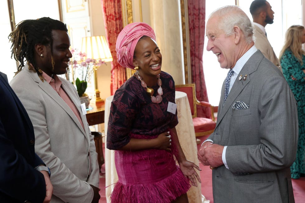 el monarca britanico sonrie con unos premiados en buckingham