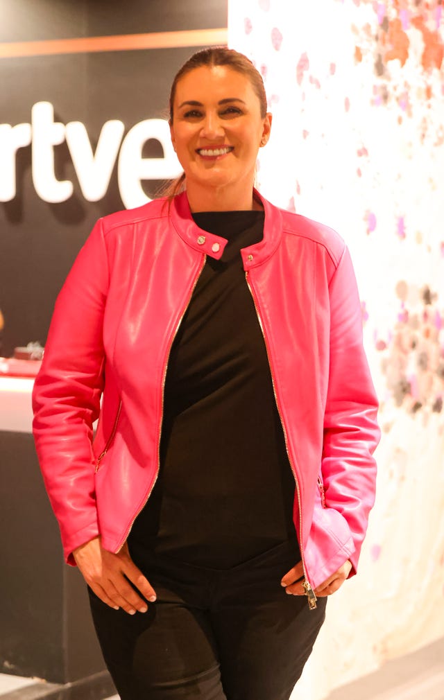 carlota corredera en el stand de rne vestida de negro con cazadora rosa de piel