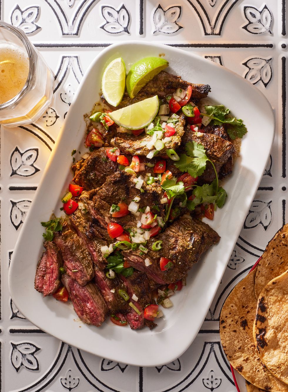 carne asada topped with pico, lime wedges, and cilantro