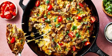 carnitas tamale pie topped with sliced cherry tomatoes, sliced scallions, and chopped cilantro