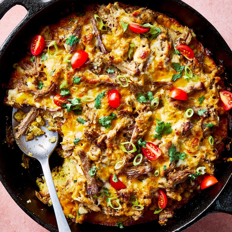 carnitas tamale pie topped with sliced cherry tomatoes, sliced scallions, and chopped cilantro