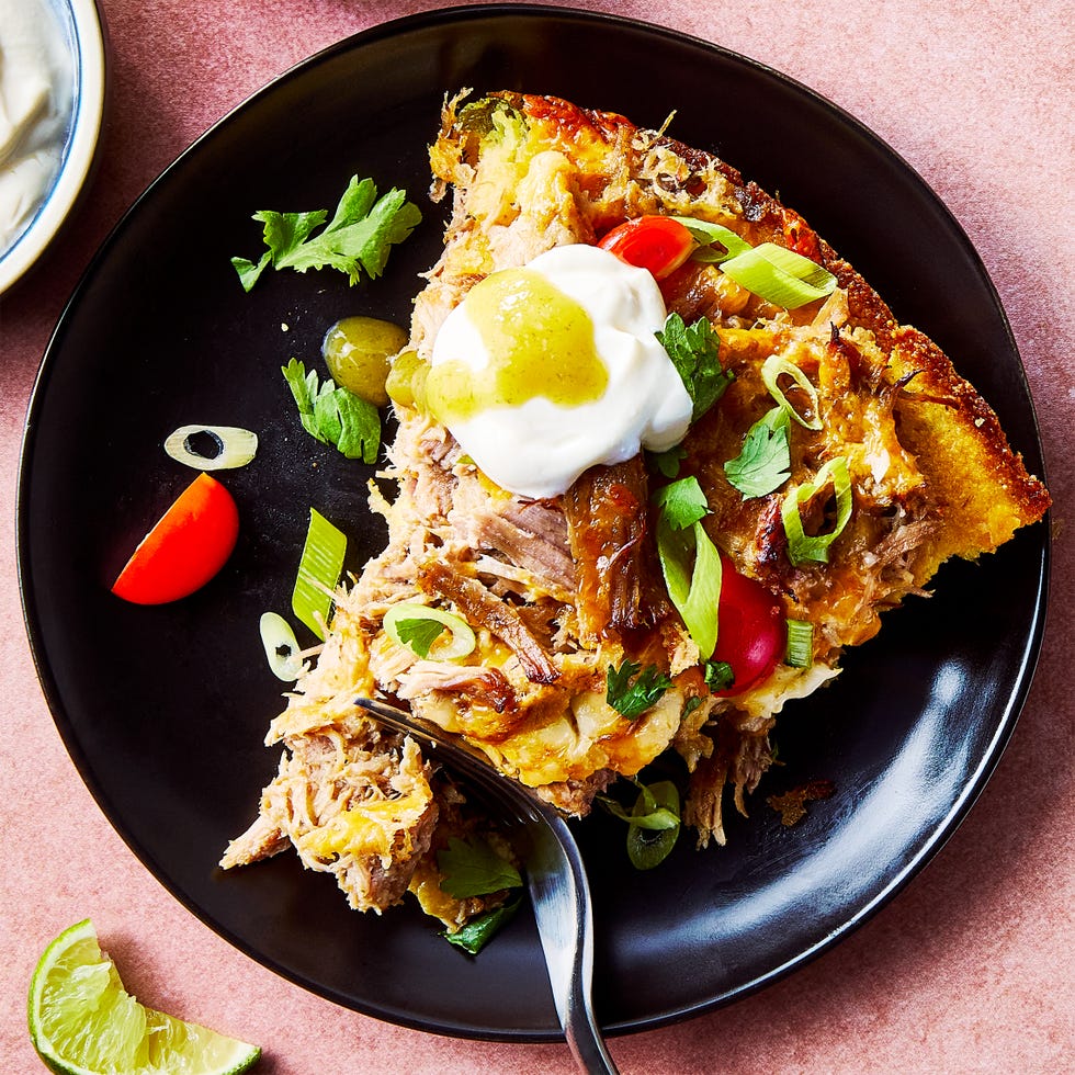 carnitas tamale pie topped with sliced cherry tomatoes, sliced scallions, and chopped cilantro