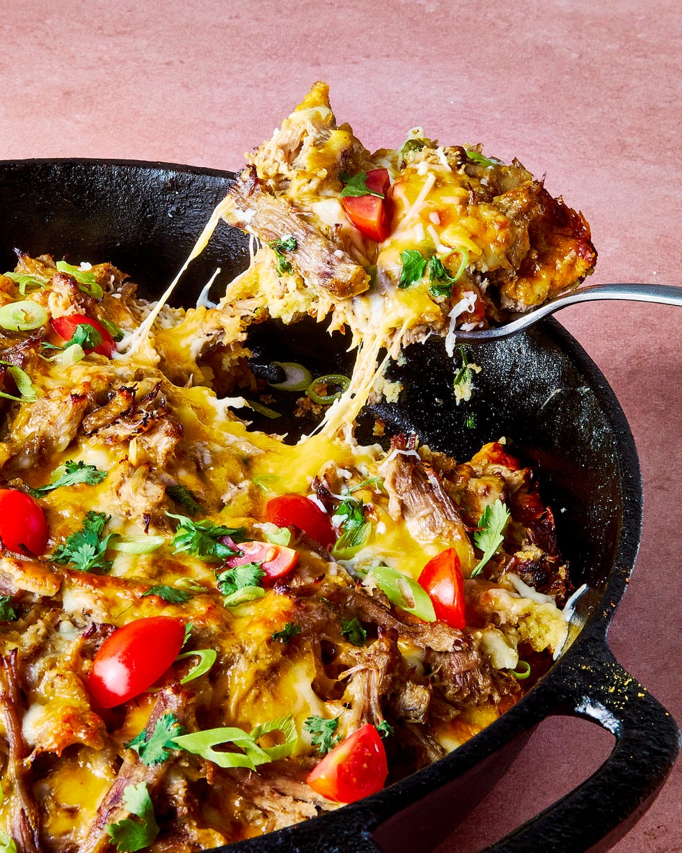 carnitas tamale pie topped with sliced cherry tomatoes, sliced scallions, and chopped cilantro