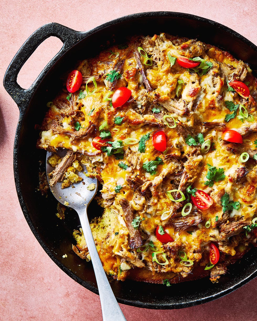 carnitas tamale pie topped with sliced cherry tomatoes, sliced scallions, and chopped cilantro