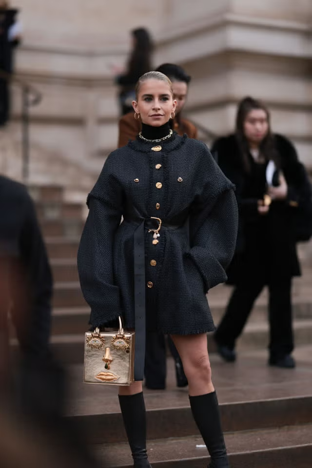 a person in a stylish black outfit and unique handbag