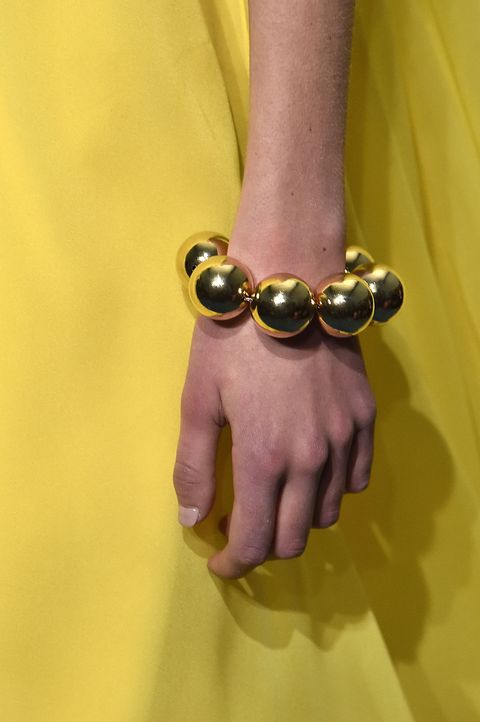 Yellow, Hand, Finger, Gesture, Holding hands, Fashion accessory, Wrist, Close-up, Interaction, Brass, 