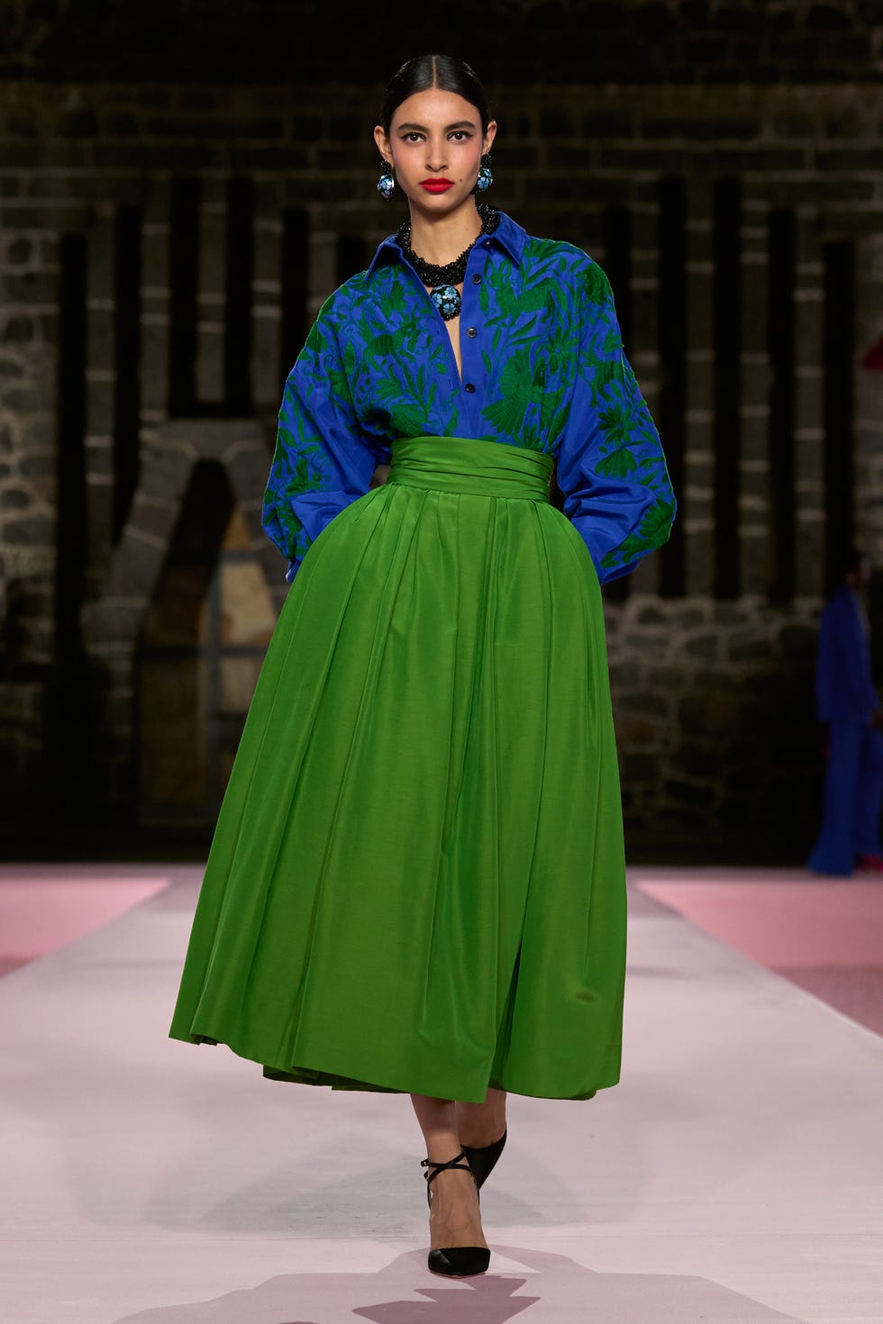 model wearing vibrant blue and green outfit on a runway