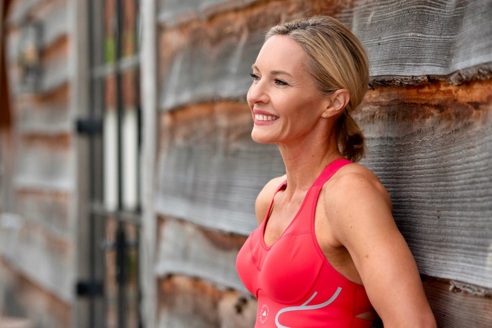person in athletic wear resting against a wooden wall