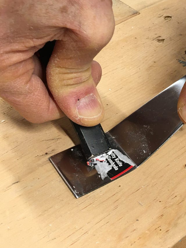 using the butt end of a carpenter's pencil to scrape off a sticker