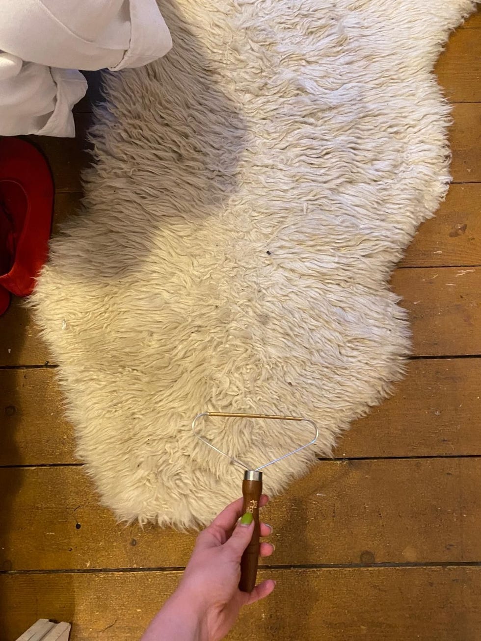 a grooming tool held over a fluffy white rug