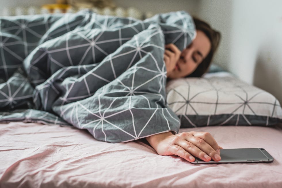 una mujer retrasa el despertador a primera hora de la mañana