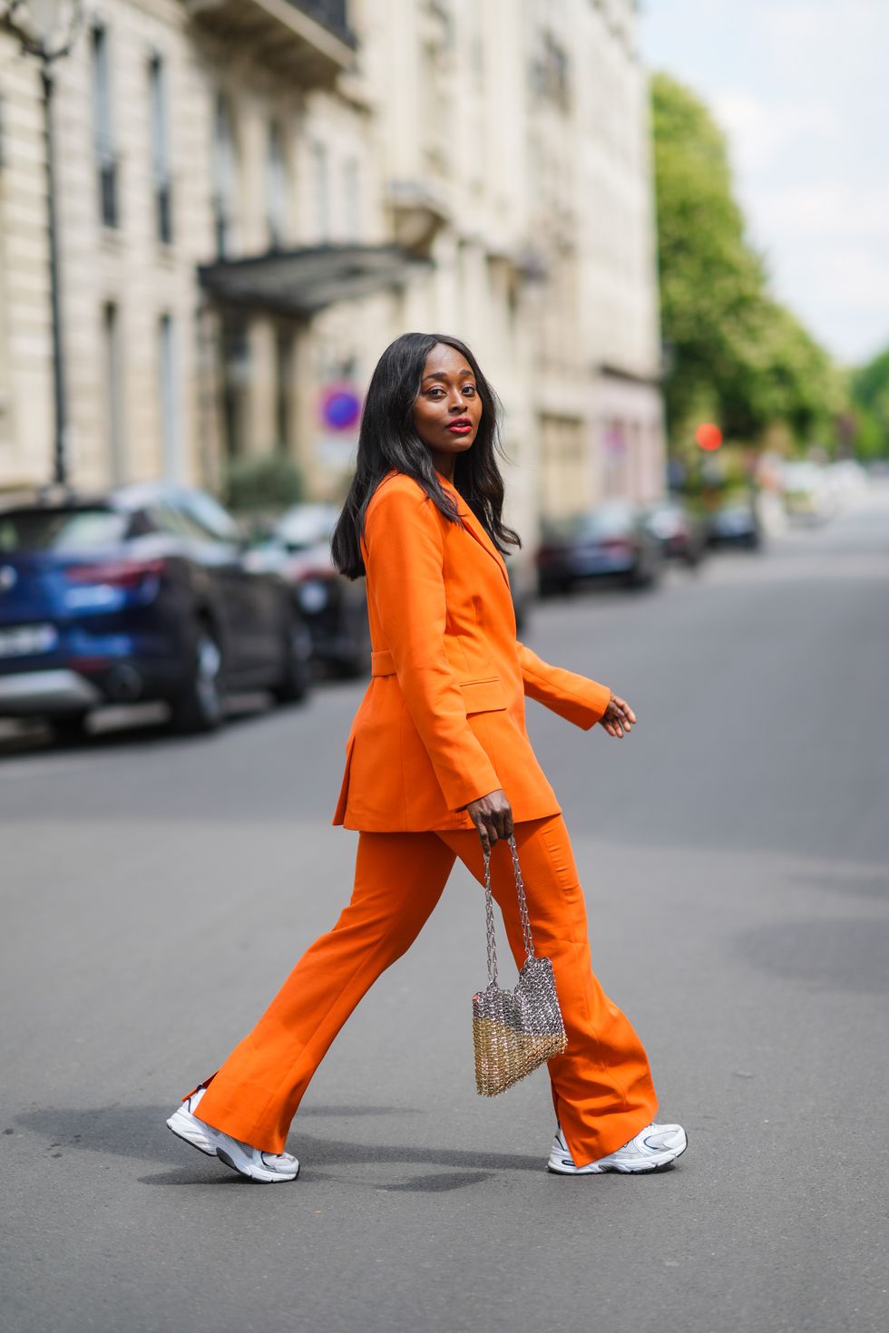 mujer posando con traje naranja y new balance