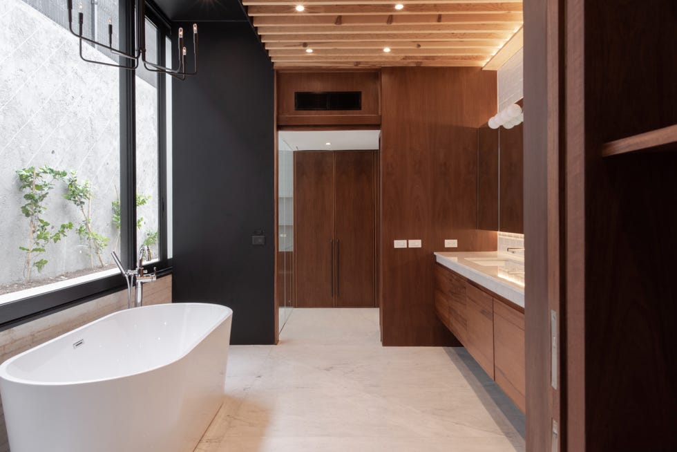 baño con mobiliario y revestimientos de madera y bañera exenta
