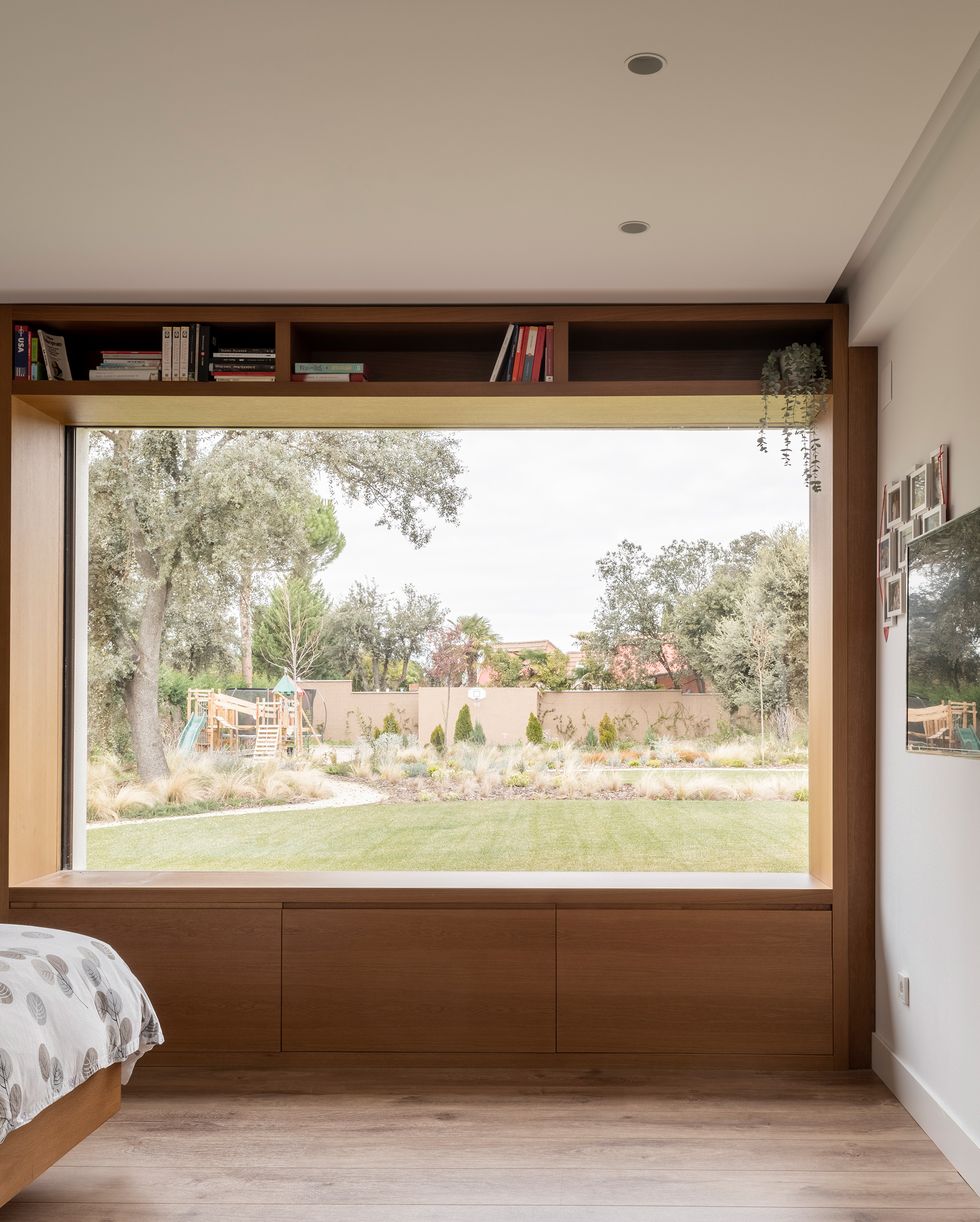 dormitorio con ventanal con vistas al jardín y estantería integrada