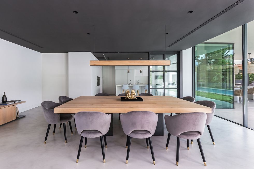comedor moderno abierto con mesa de madera y sillas tapizadas en terciopelo gris