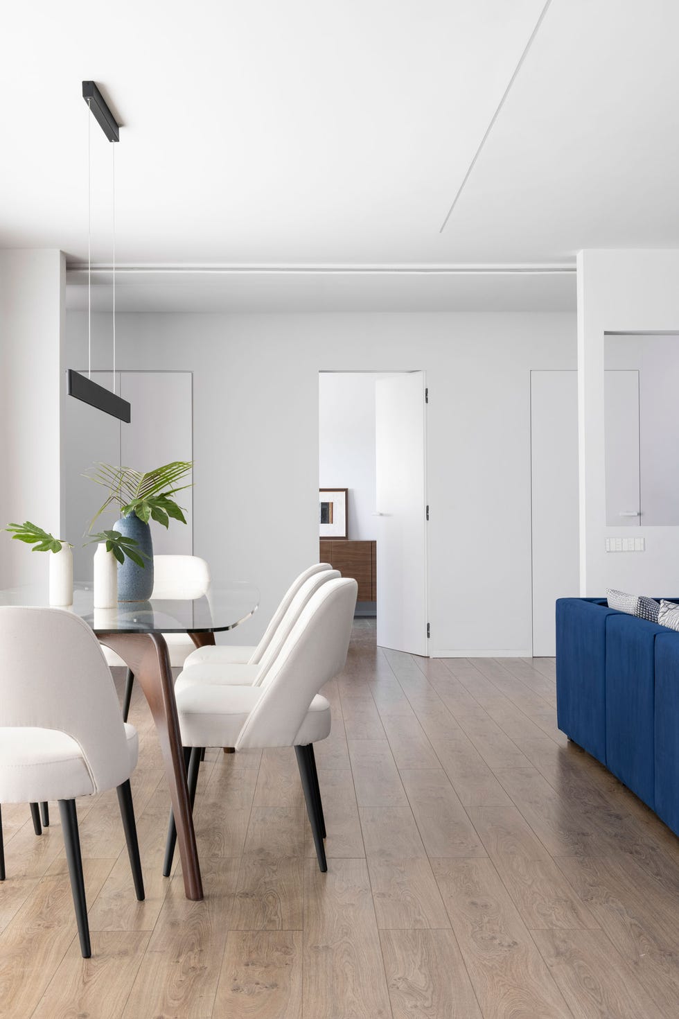 comedor formal con mesa de madera y sobre de cristal y sillas tapizadas en blanco