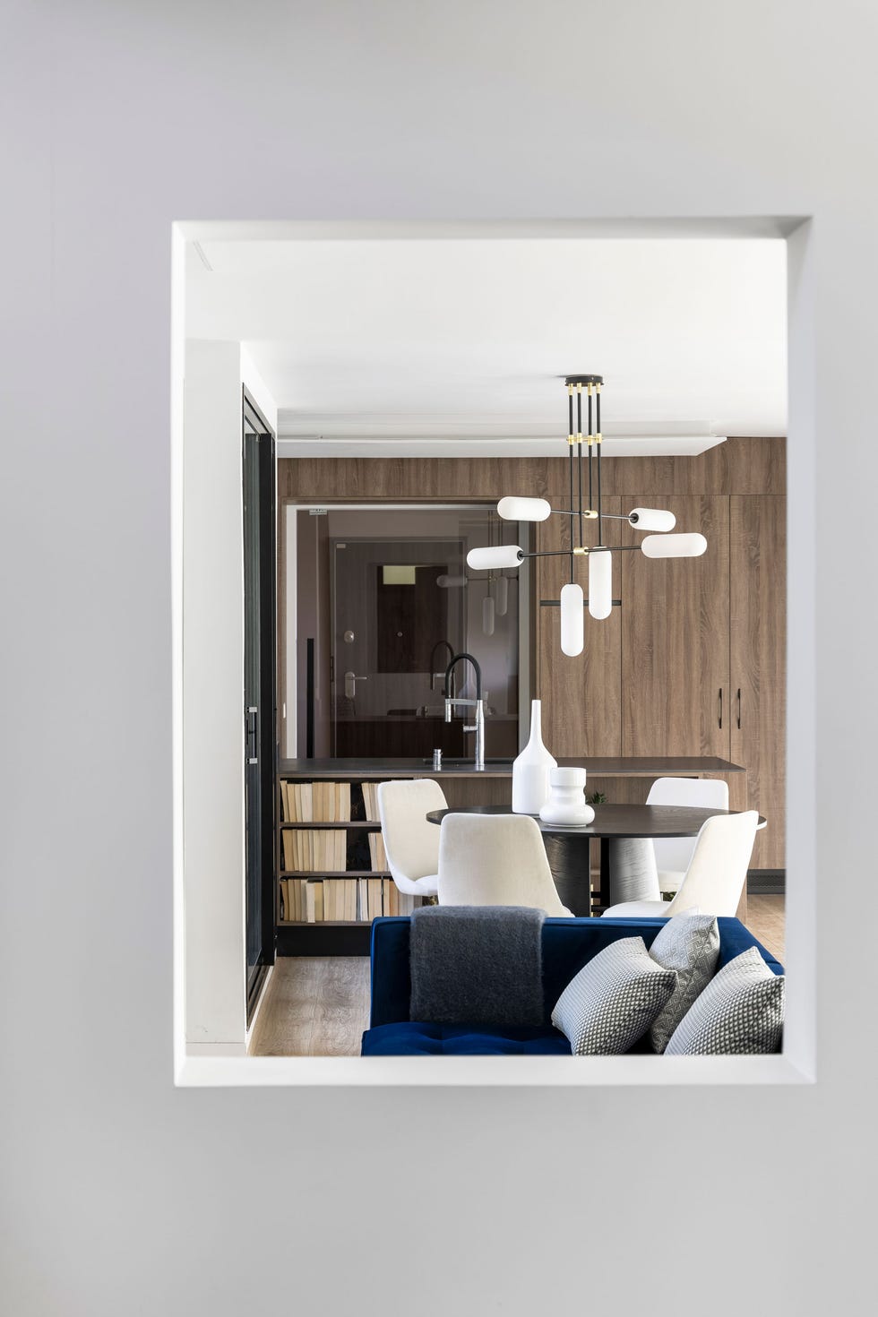 comedor de diseño contemporáneo y minimalista con mesa redonda y sillas tapizadas en gris y librería al fondo