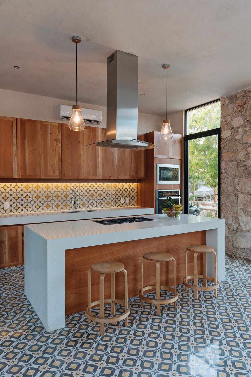 cocina con isla central de mármol y madera y suelo de baldosas geométricas