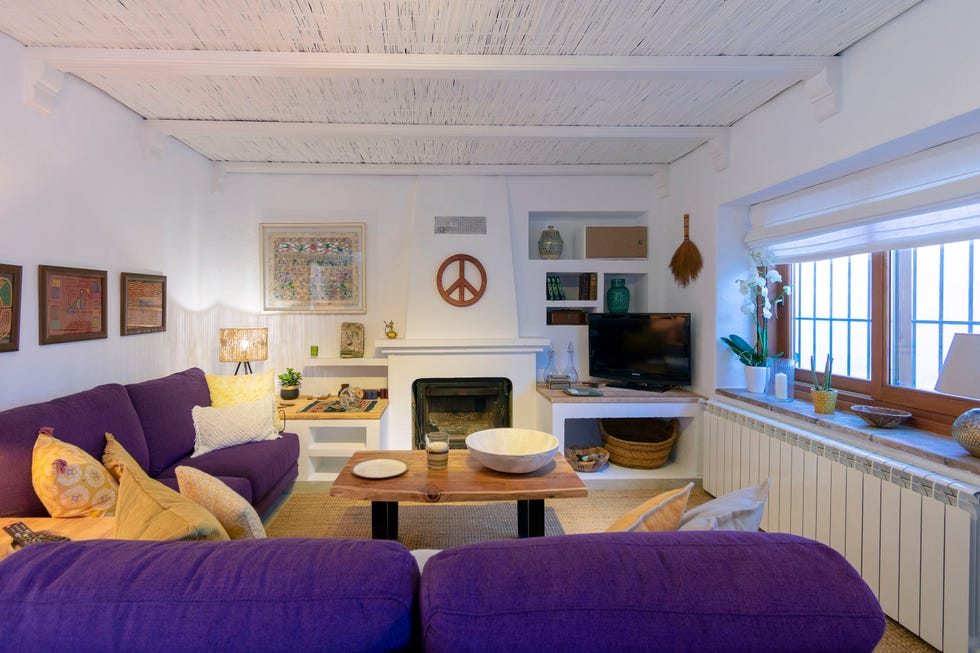 salón con chimenea de estilo ecléctico con un sofá púrpura