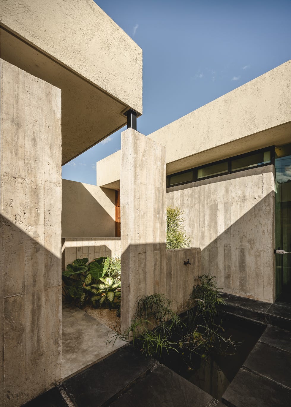 casa de hormigon, estrecha y alargada, que resuelve la distribucion en dos volumenes conectados por un patio