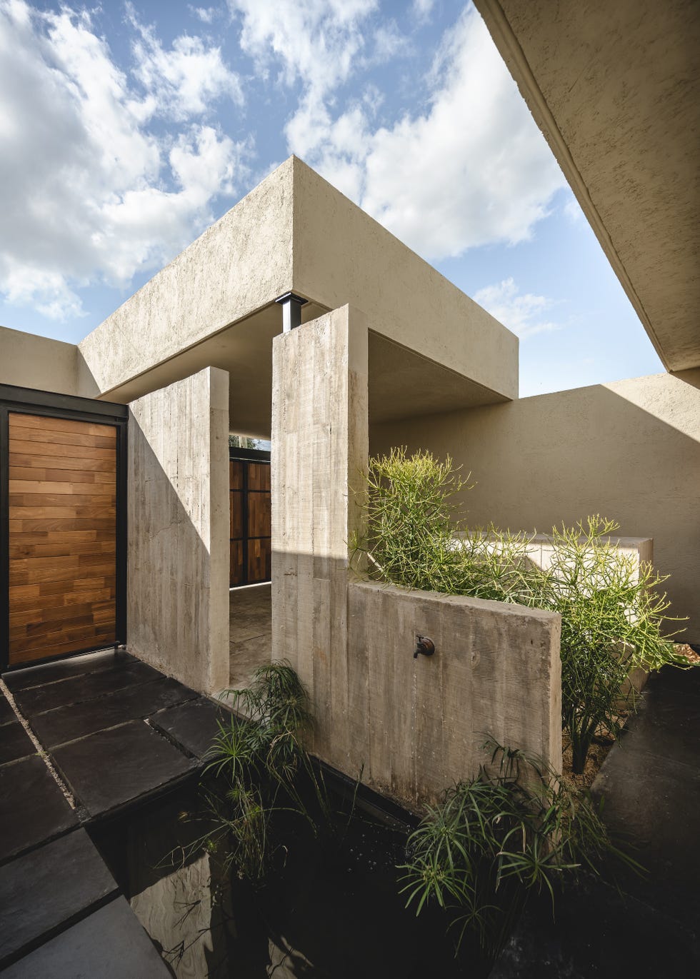 casa de hormigon, estrecha y alargada, que resuelve la distribucion en dos volumenes conectados por un patio