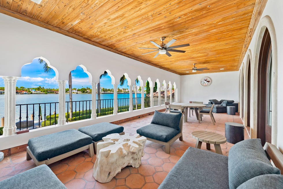 terraza de estilo colonial con sofás y sillones grises y techo de lamas de madera