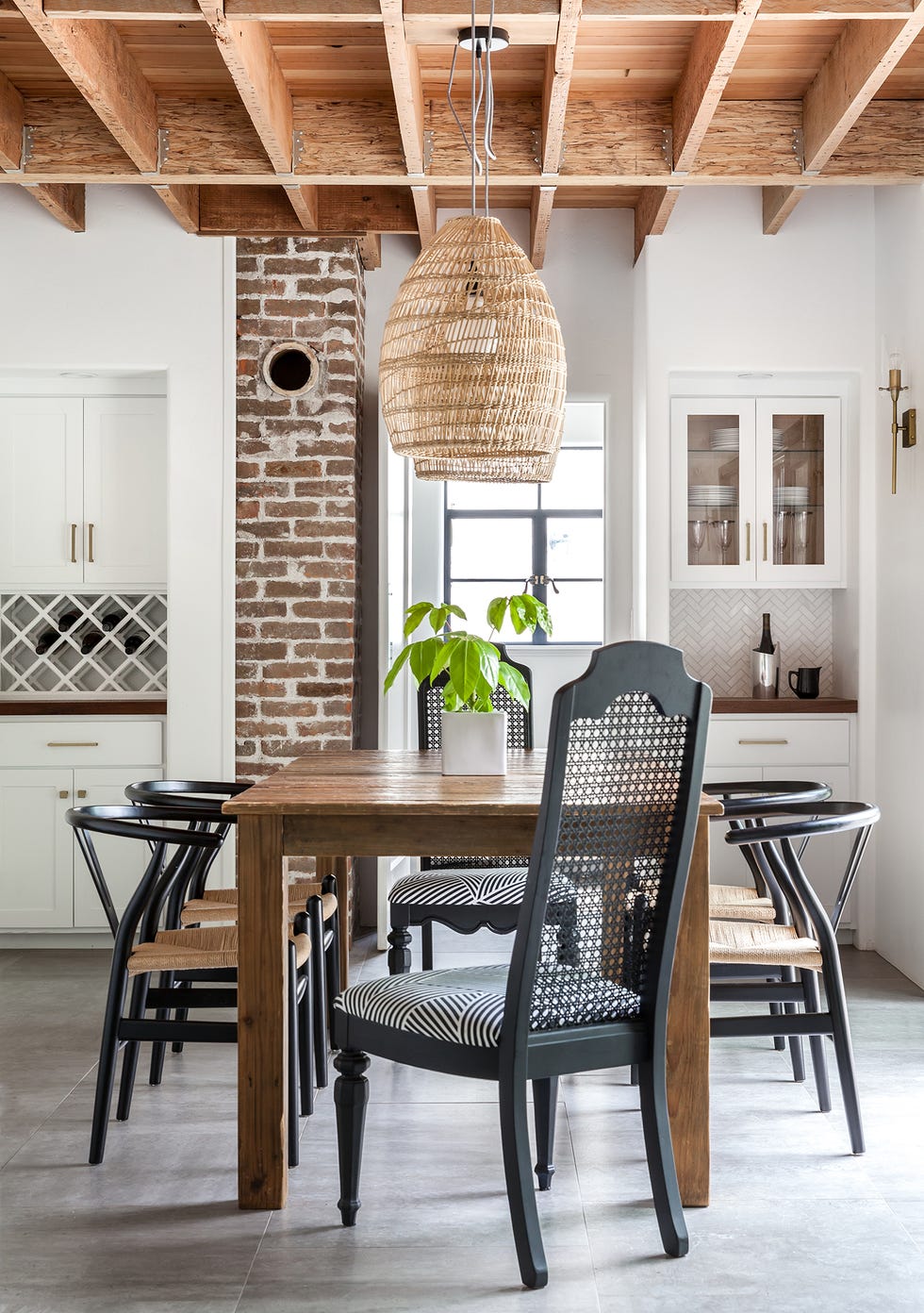 comedor con mesa de madera, sillas con asientos trenzados y lámpara de techo de fibras