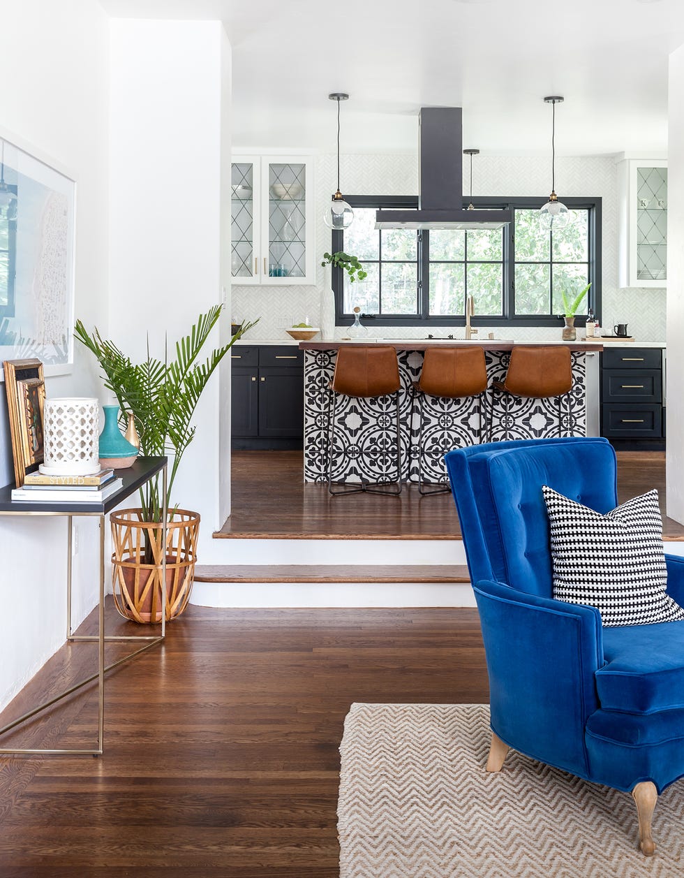 cocina abierta y moderna con isla central revestida con azulejos y tres taburetes de piel marrón