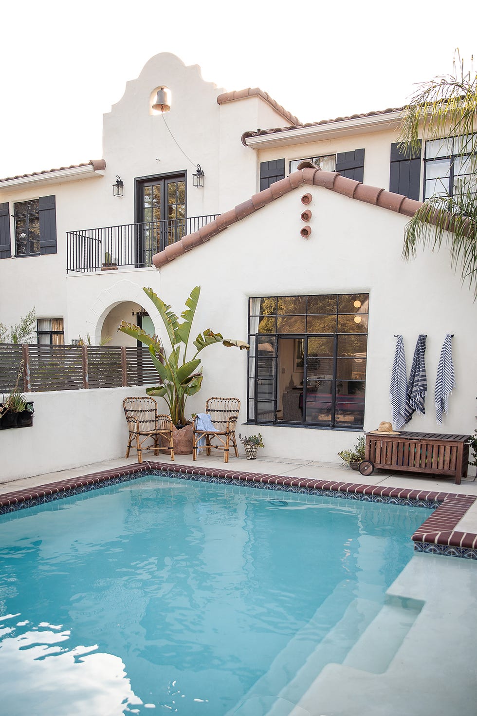 piscina con dos butacas de ratán y una palmera