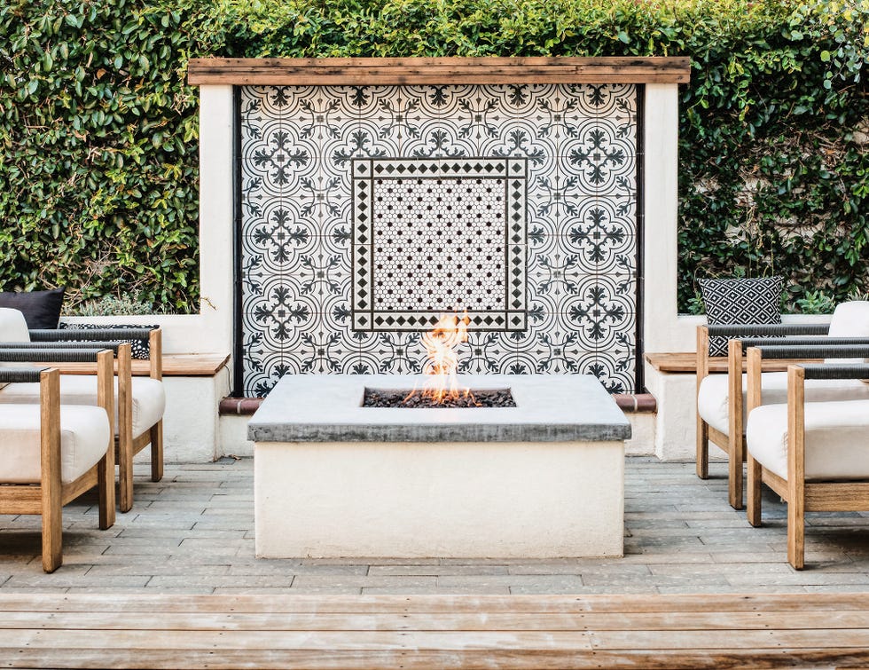 terraza con zona de asientos, brasero de obra y mural de azulejos en la pared