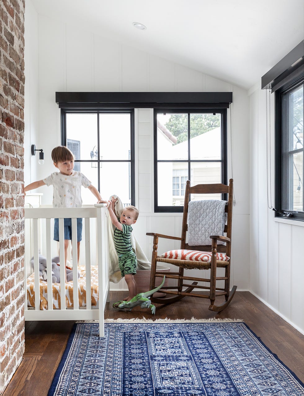 habitación infantil con cuna blanca y una mecedora de madera vintage