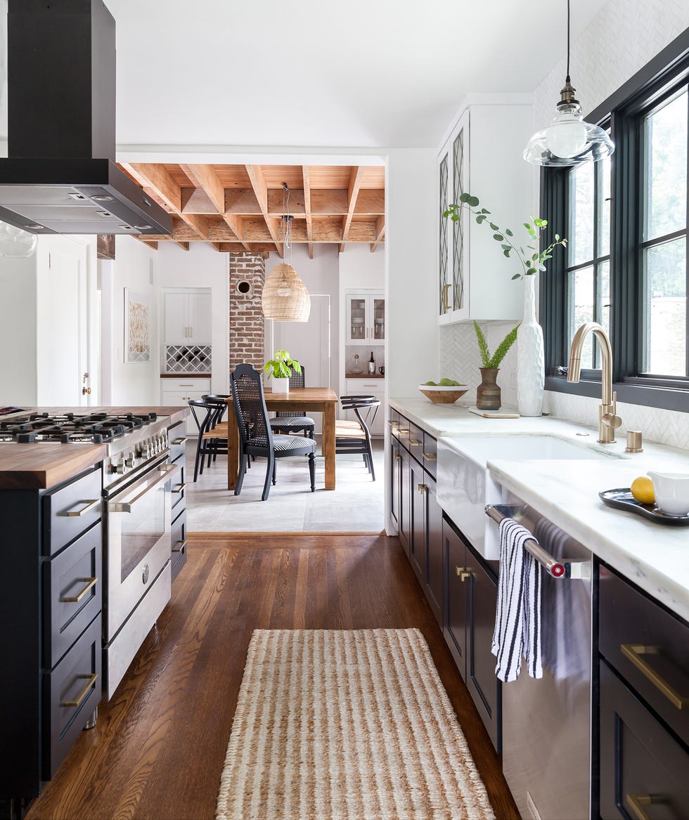 cocina abierta con isla central, decorada con armarios negros y encimeras blancas