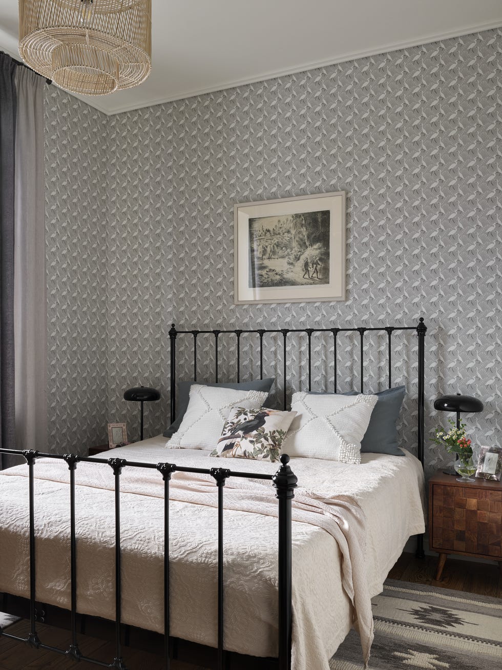 dormitorio con cama de forja negra y papel pintado con flamencos en tonos grises