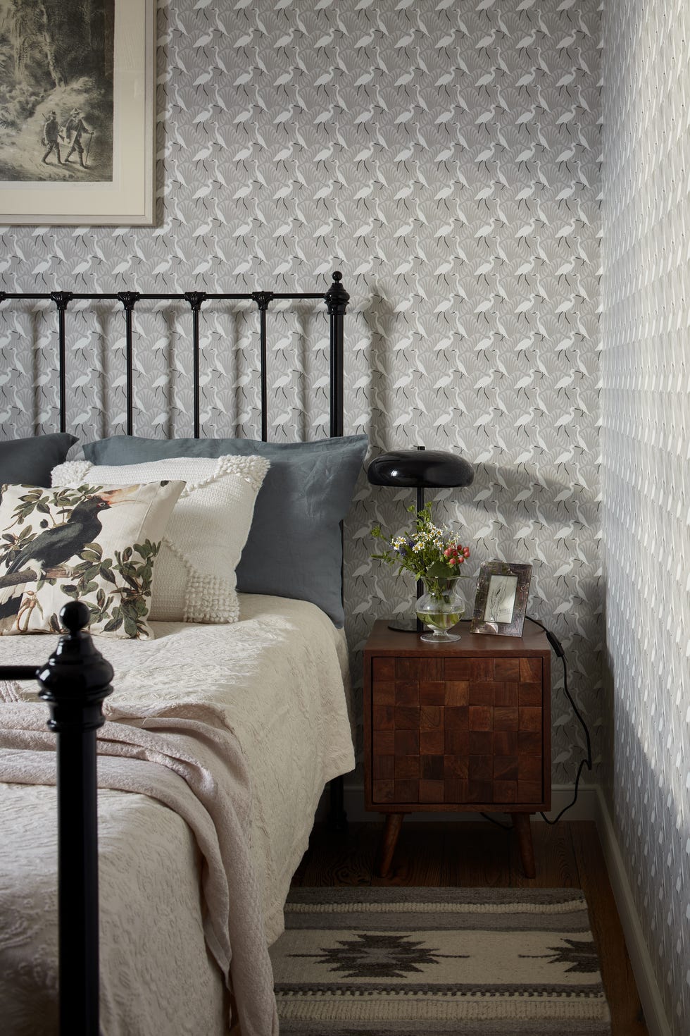 dormitorio con cama de forja negra y papel pintado con flamencos en tonos grises