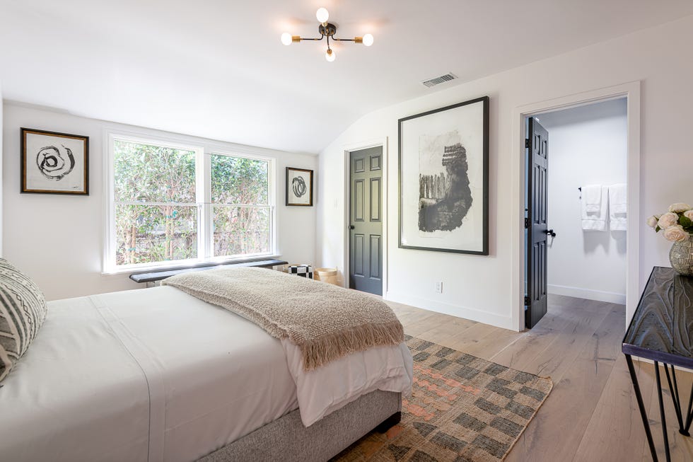 dormitorio moderno con baño en suite, alfombra kilim y cama tapizada en tela gris
